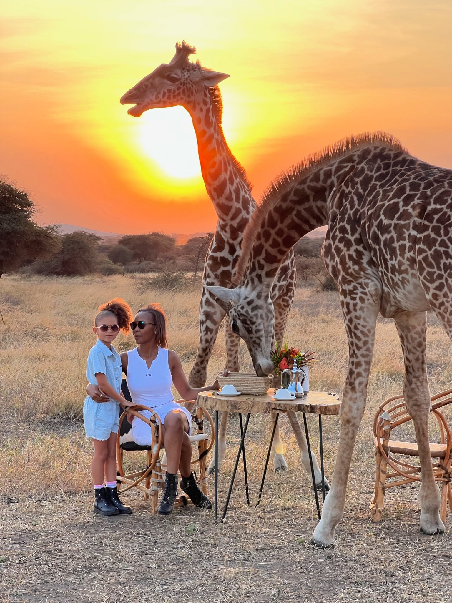 Mother and child beside giraffes at sunset during a Serval Wildlife day visit