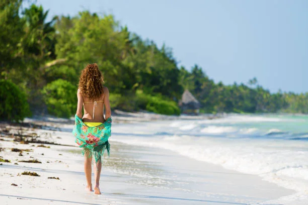 Traveller walking along a white-sand beach beside the Indian Ocean