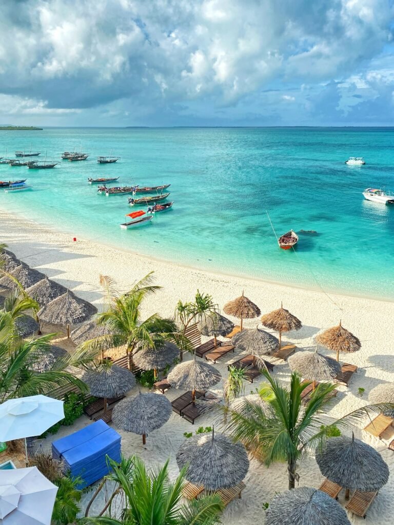 Wooden boats in turquoise water beside a sandy beach — island holidays with Tartaruga Safaris