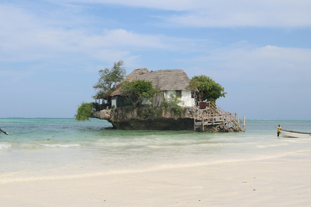 Restaurante com teto de palha sobre uma rocha junto à praia em Zanzibar
